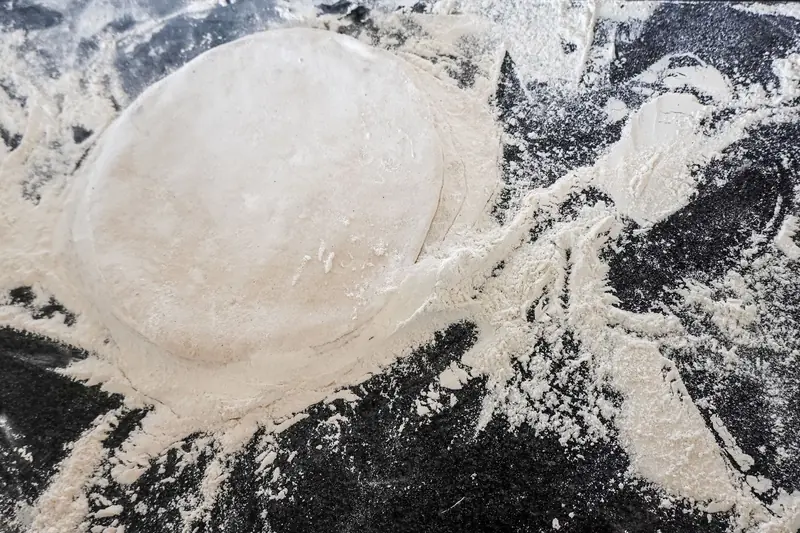 Top view of raw pizza dough on a flour-covered counter, perfect for Italian culinary themes