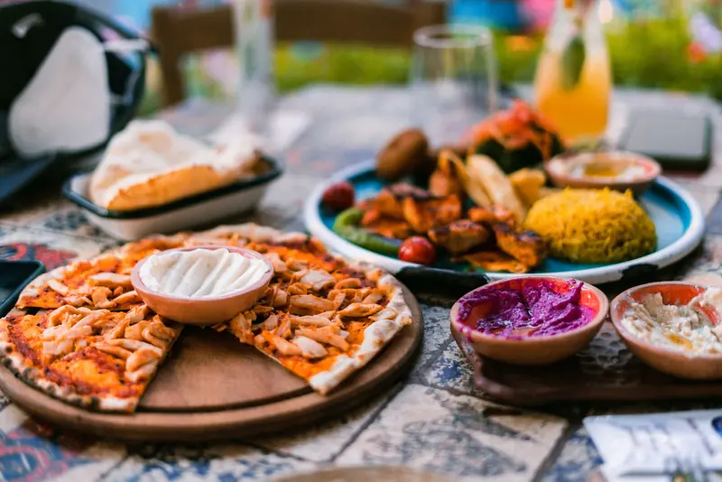 Close-up of a Mediterranean table spread featuring pizza, dips, and diverse dishes, inviting and colorful