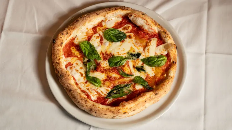 Classic Neapolitan Margherita pizza topped with fresh basil, mozzarella, and tomato sauce