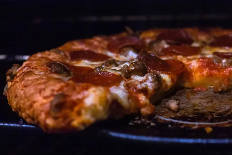 Delicious pepperoni pizza baking in oven with melted cheese and crispy crust