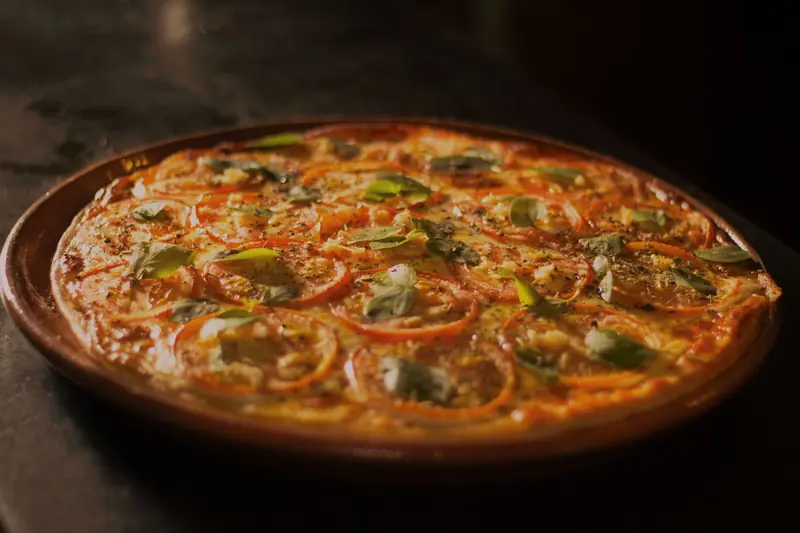 Close-up of a mouth-watering pizza topped with fresh basil, tomato, and mozzarella, capturing the essence of Italian cuisine