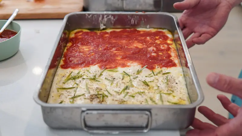 Baked homemade pizza with tomato and rosemary toppings in a rectangular pan