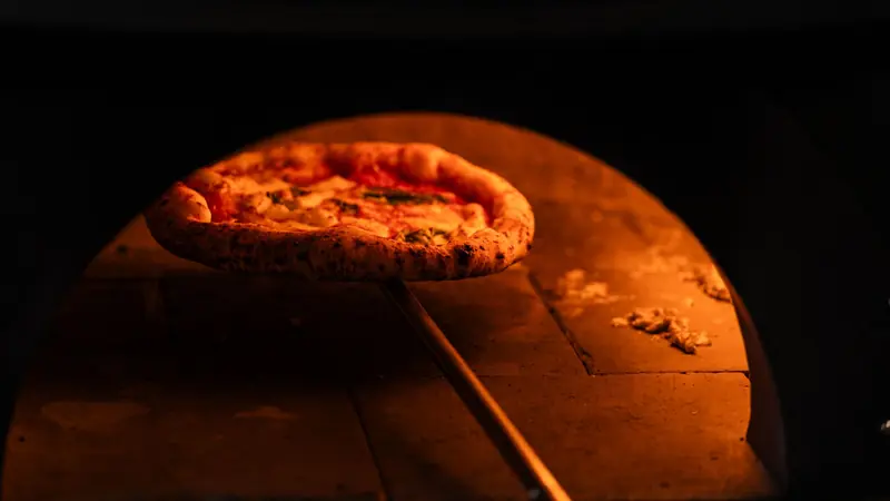 Delicious Neapolitan pizza baking in a rustic wood-fired oven, capturing the essence of traditional pizza making