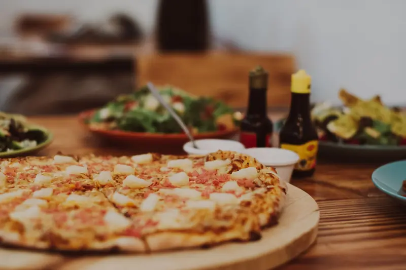 Close-up of a tasty Hawaiian pizza with pineapple and ham toppings on a wooden table